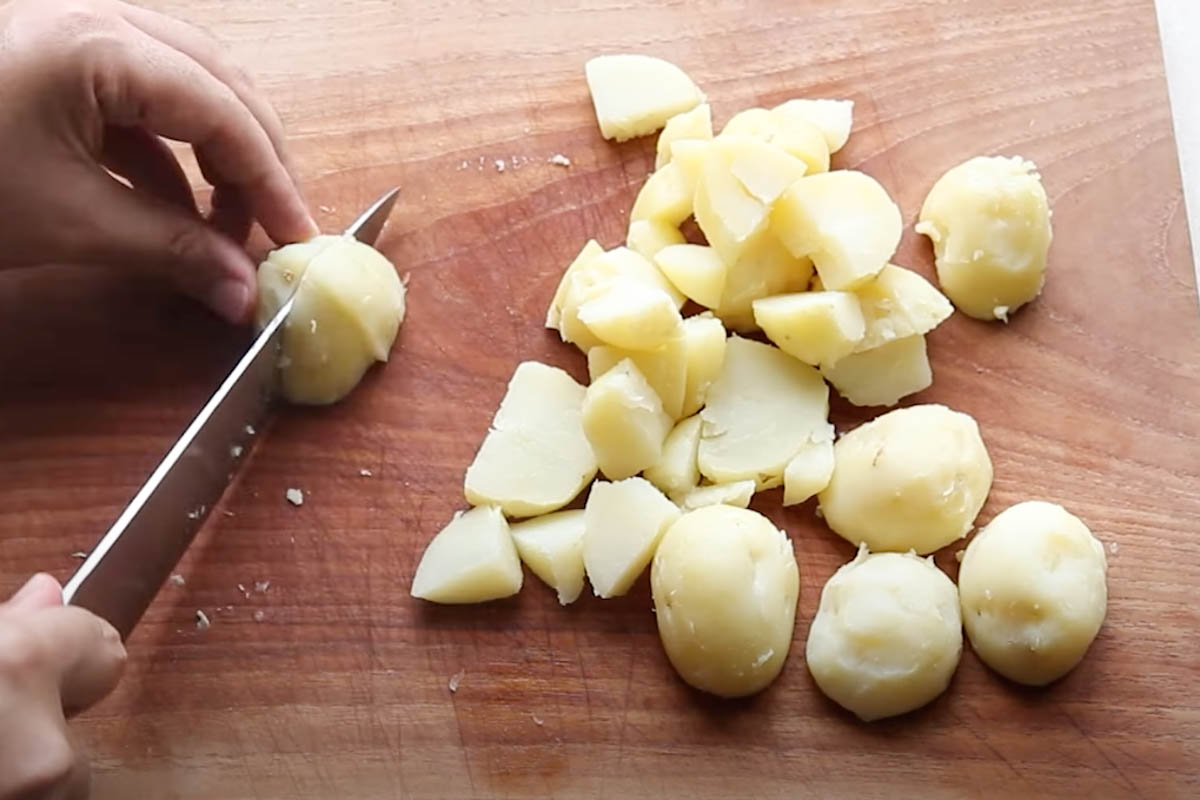 Chopping potatoes into chunks on a wooden board