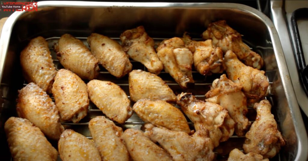 Cooked chicken wings in a baking tray on a wire rack