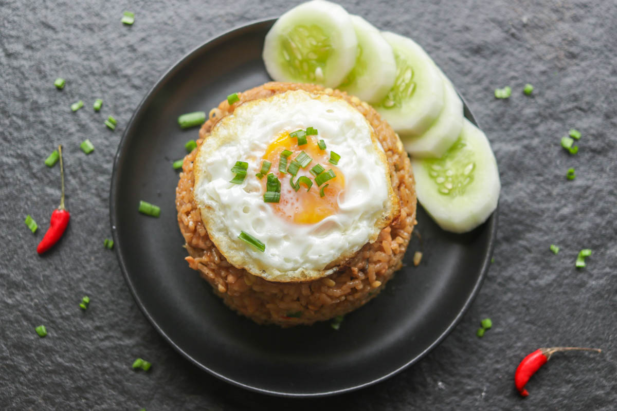 Nasi goreng on a plate with a fried egg and peeled cucumber 
