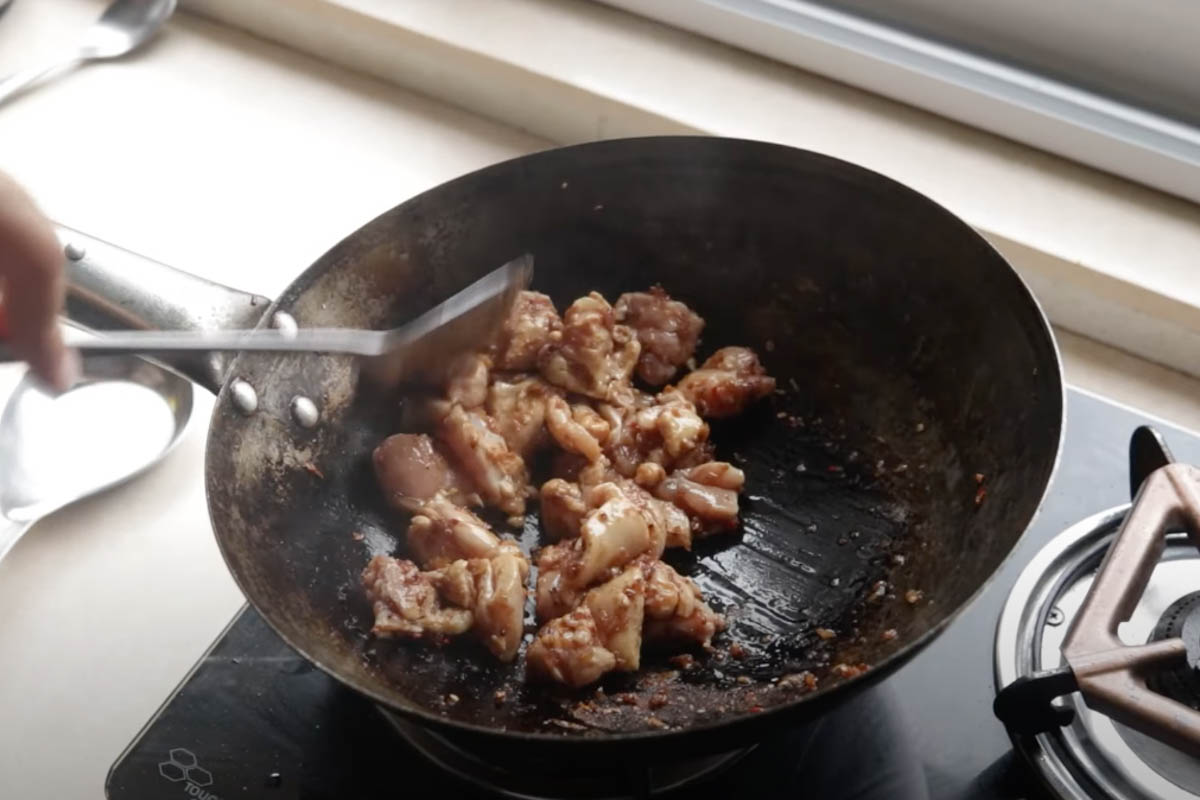 Chicken stir frying in a wok with nasi goreng paste