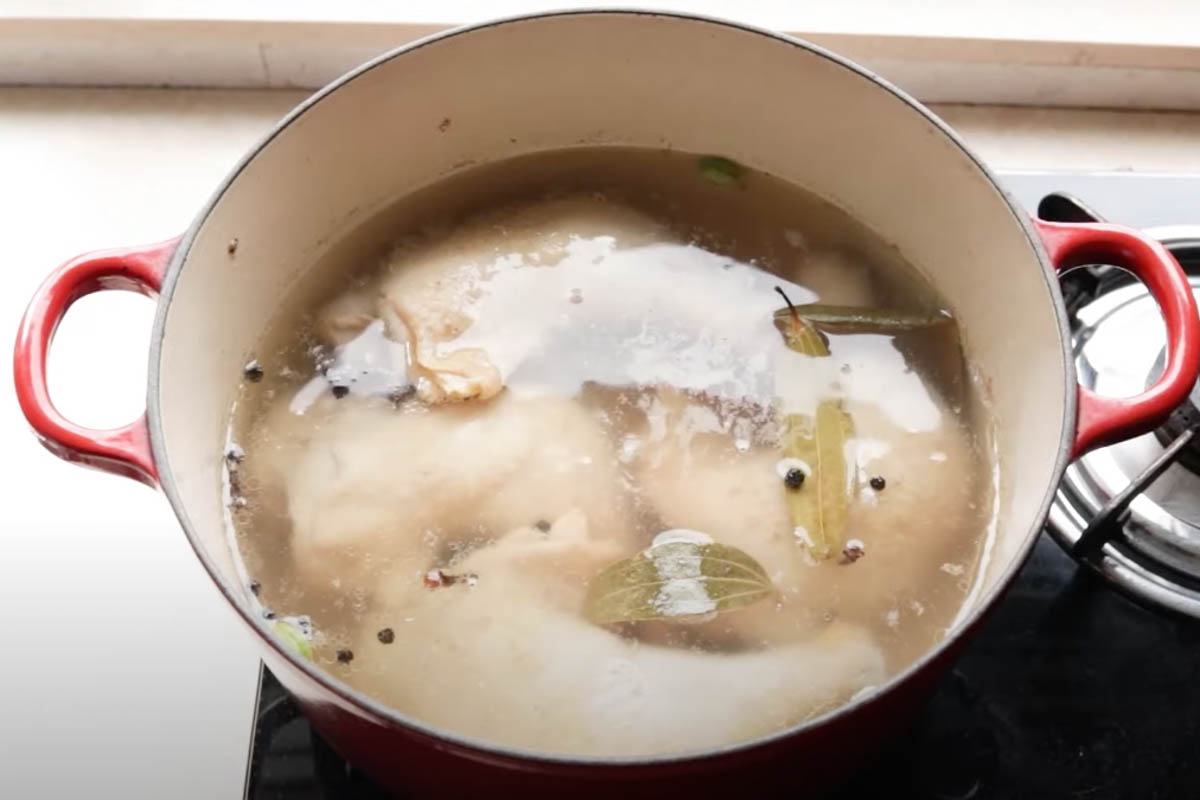 Chicken legs and spices cooking in a pot of water