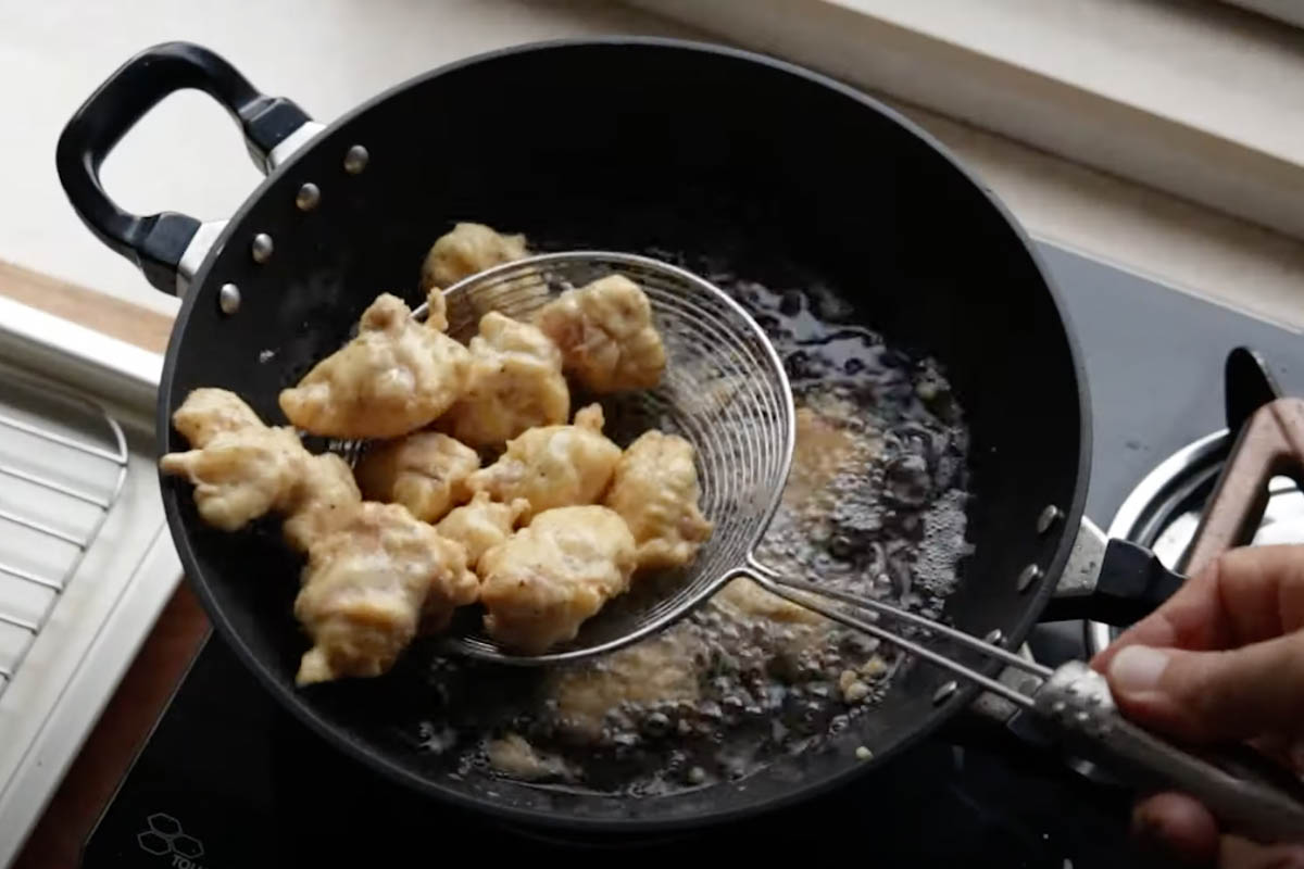 Taking a batch of fried chicken out of oil