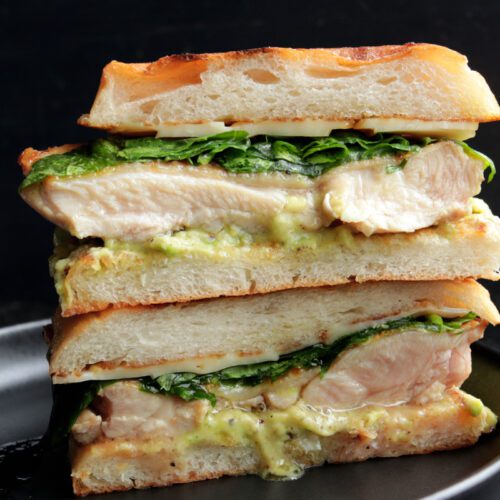 Chicken and avocado sandwich cut in half on a plate