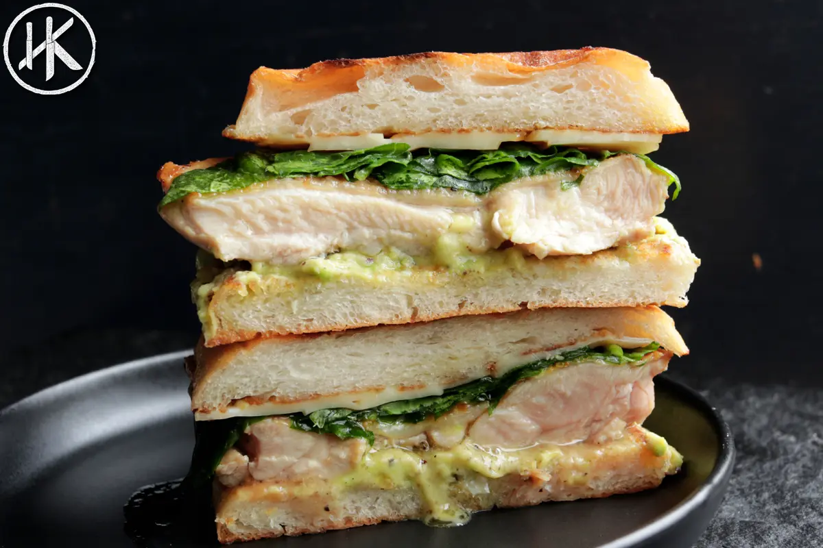 Chicken and avocado sandwich cut in half on a plate